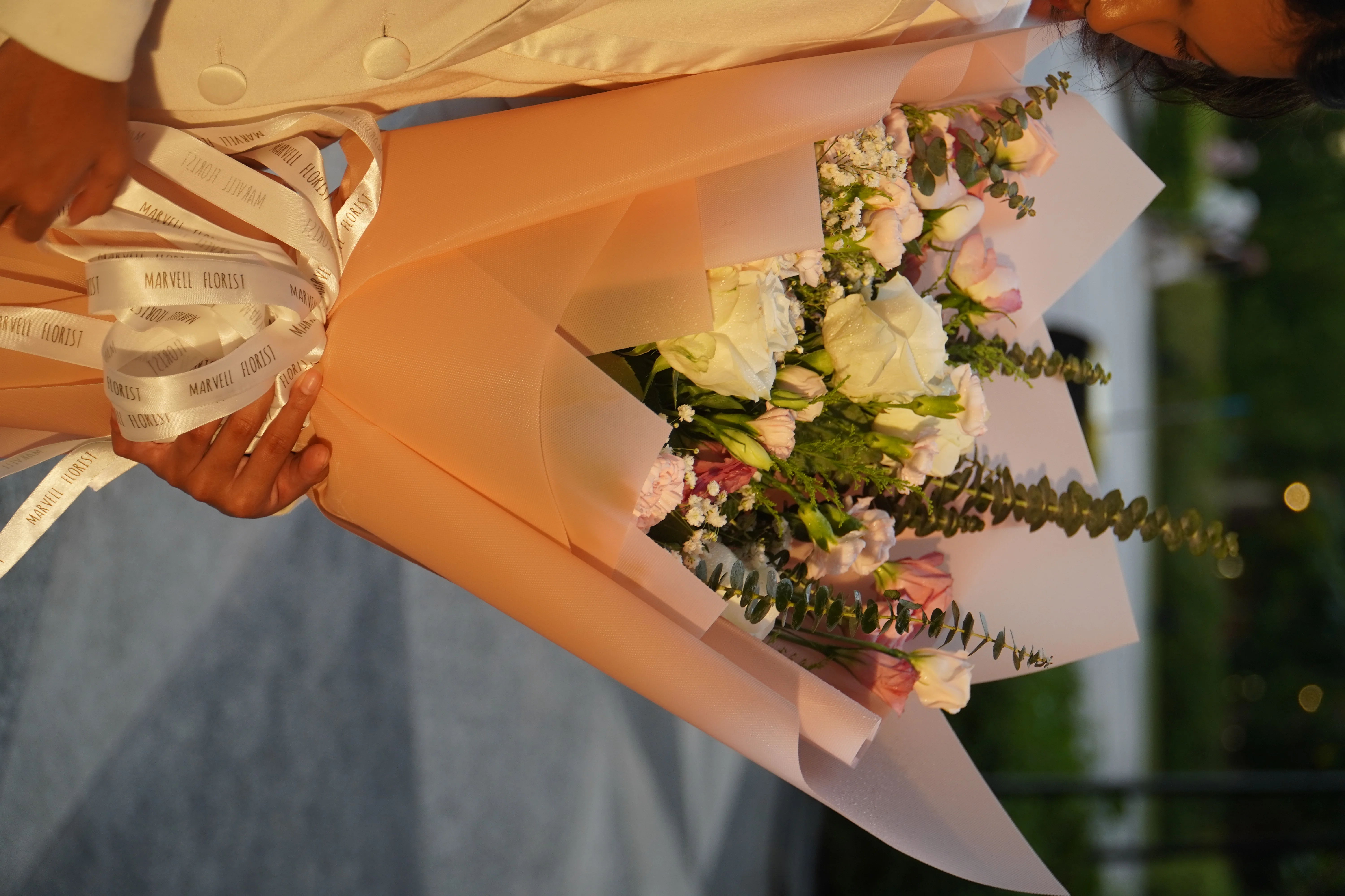 A close-up of a bouquet being finished with ribbon and wrapping