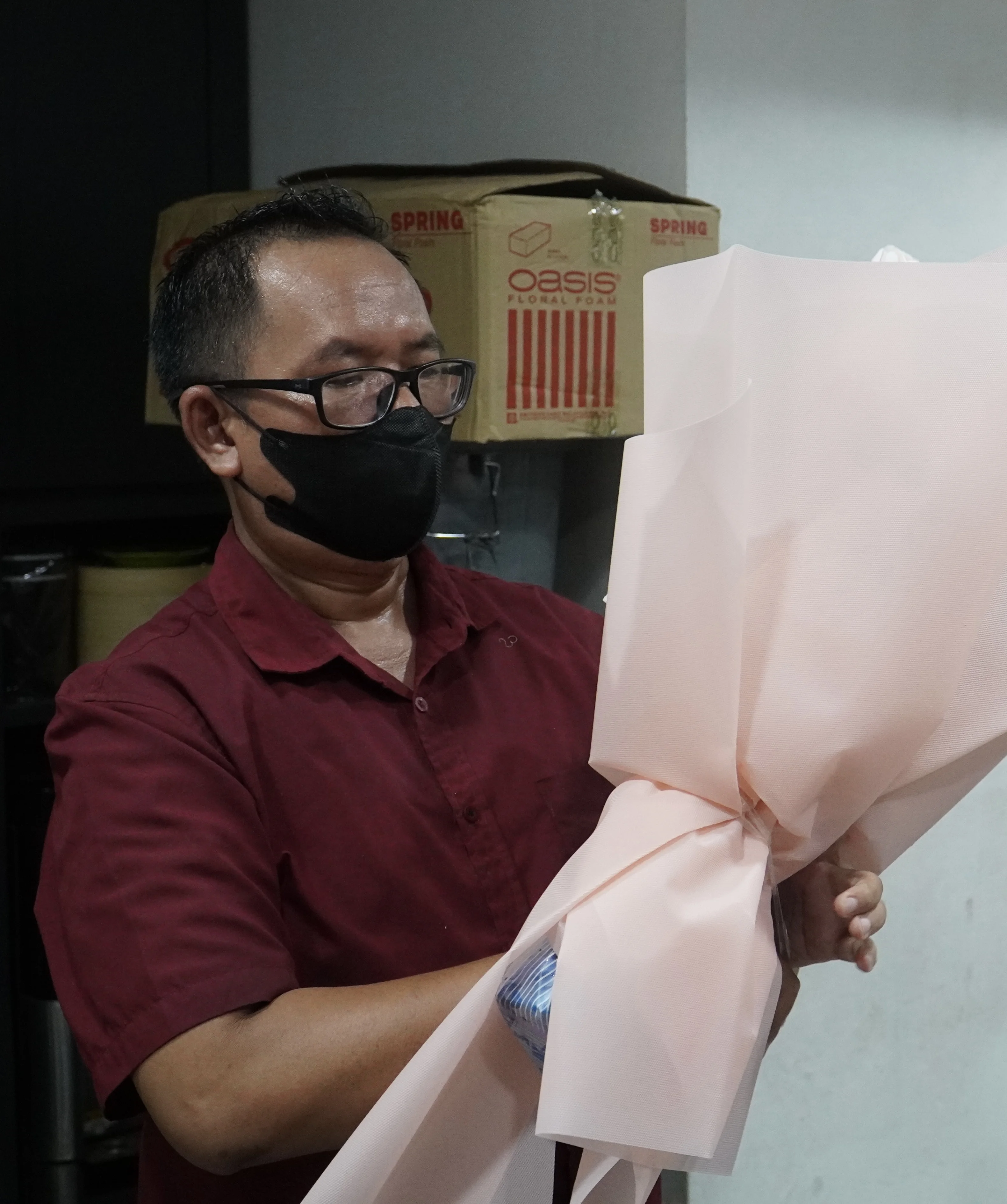 A florist preparing and holding a wrapped bouquet inside the store